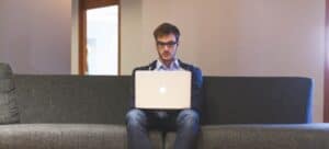 A man sitting and holding a laptop. To find romantic music for a wedding video, you have to do good research.